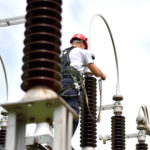 Electrician with Protective Workwear, Hardhat and Safety Harness Working